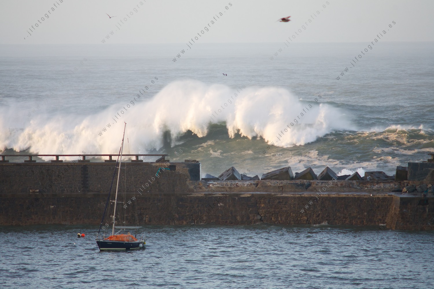 Imagen aterradora del dique del puerto reventado por el oleaje con olas que siguen golpeando