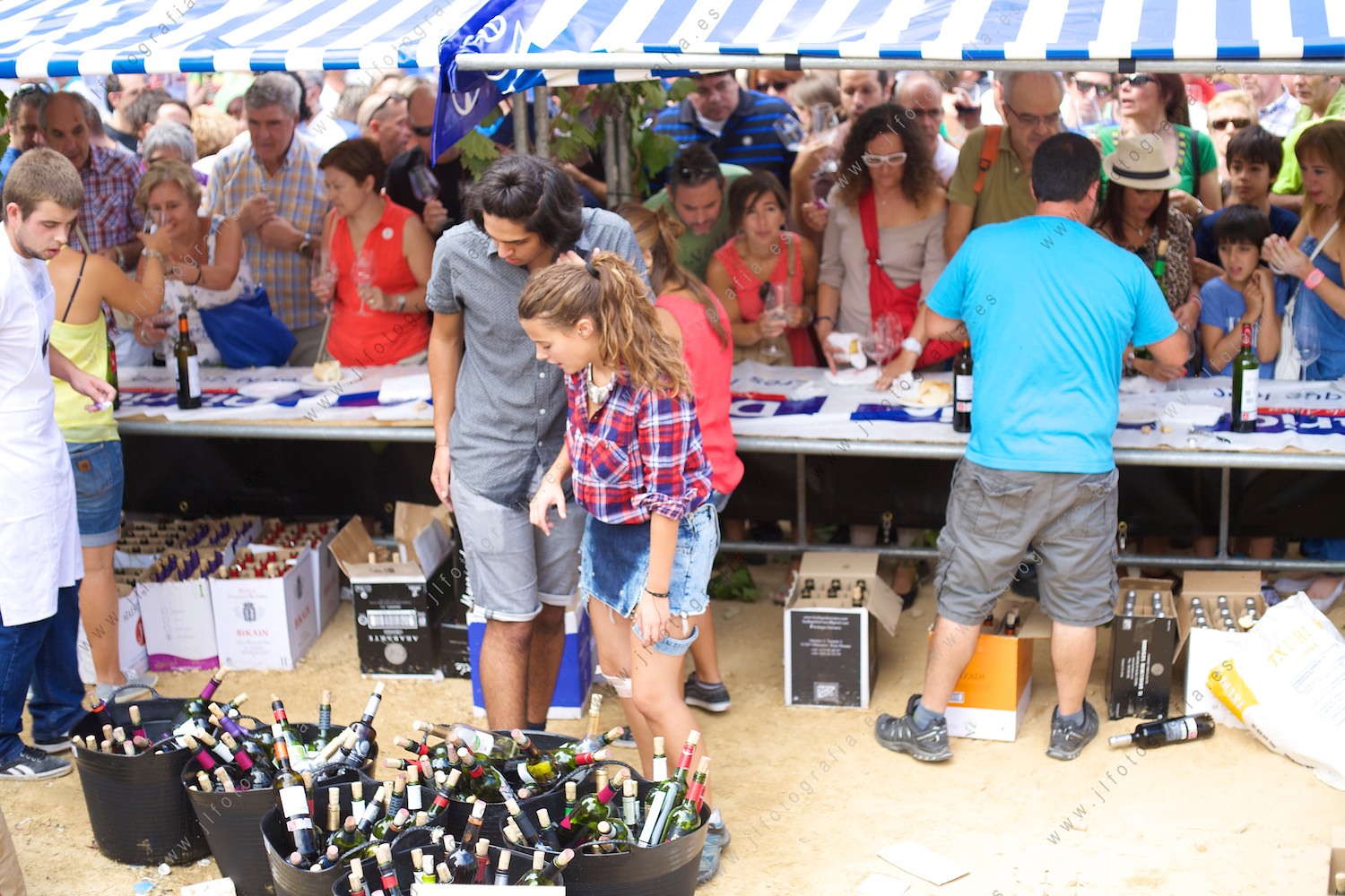 Muchísima gente en la fiesta de la vendimia en Labastida y los puestos de venta de vino con muchas botellas vaciadas