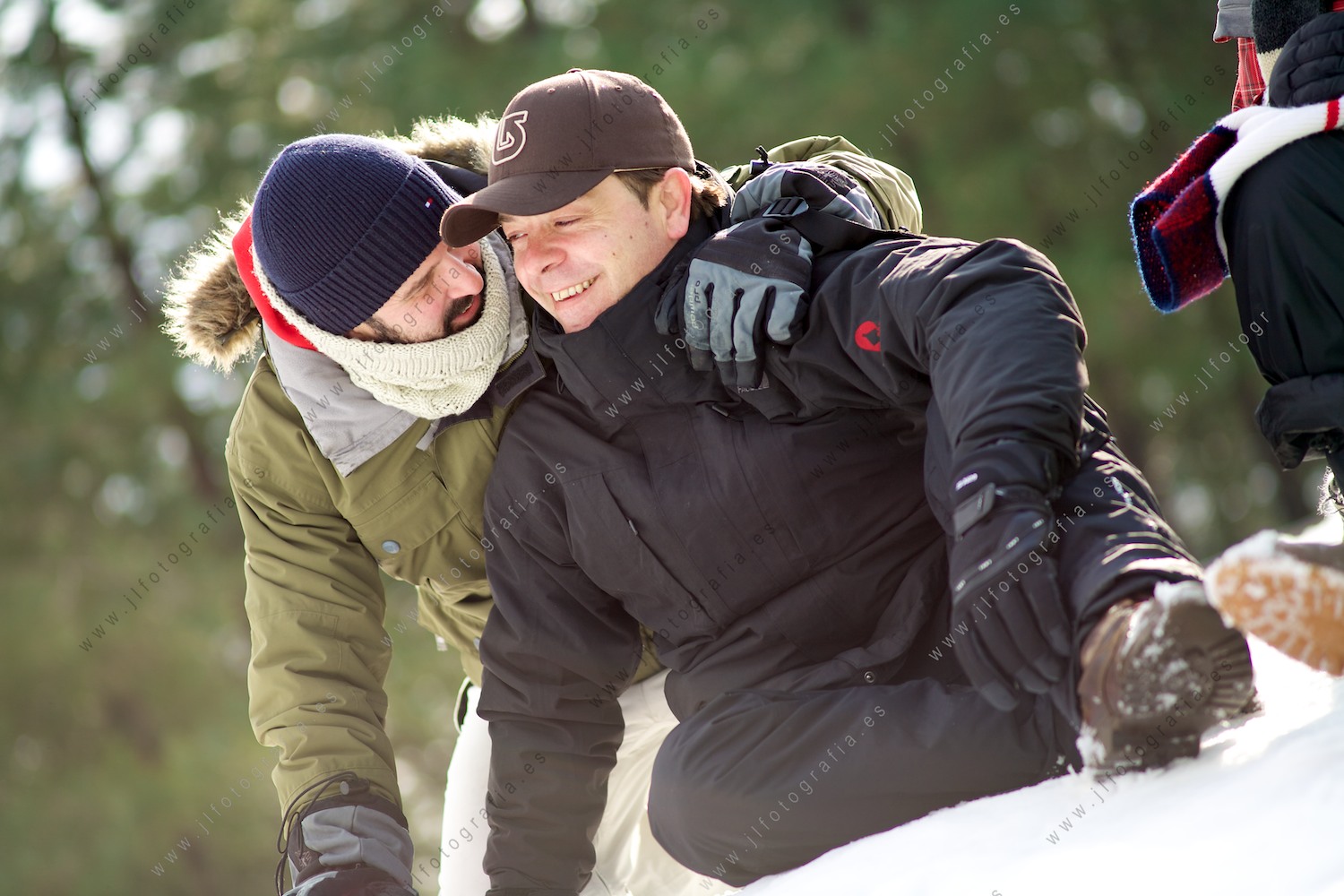 retrato de dos amigos abrazados comentando, sentados en la nieve 