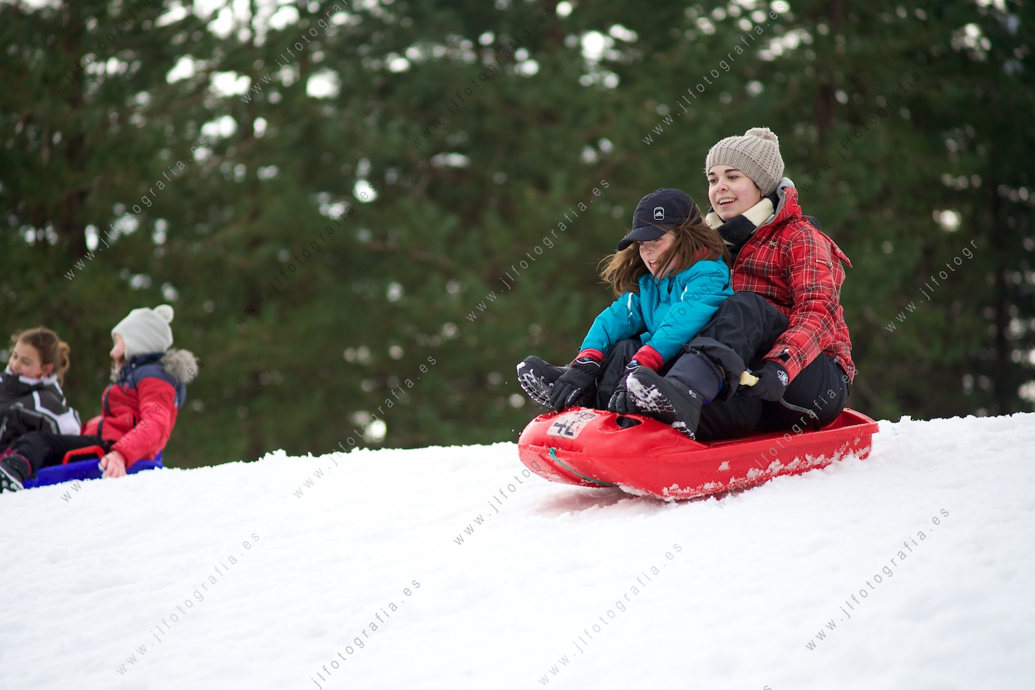 Dos hermanas descendiendo por la nieve en un trineo