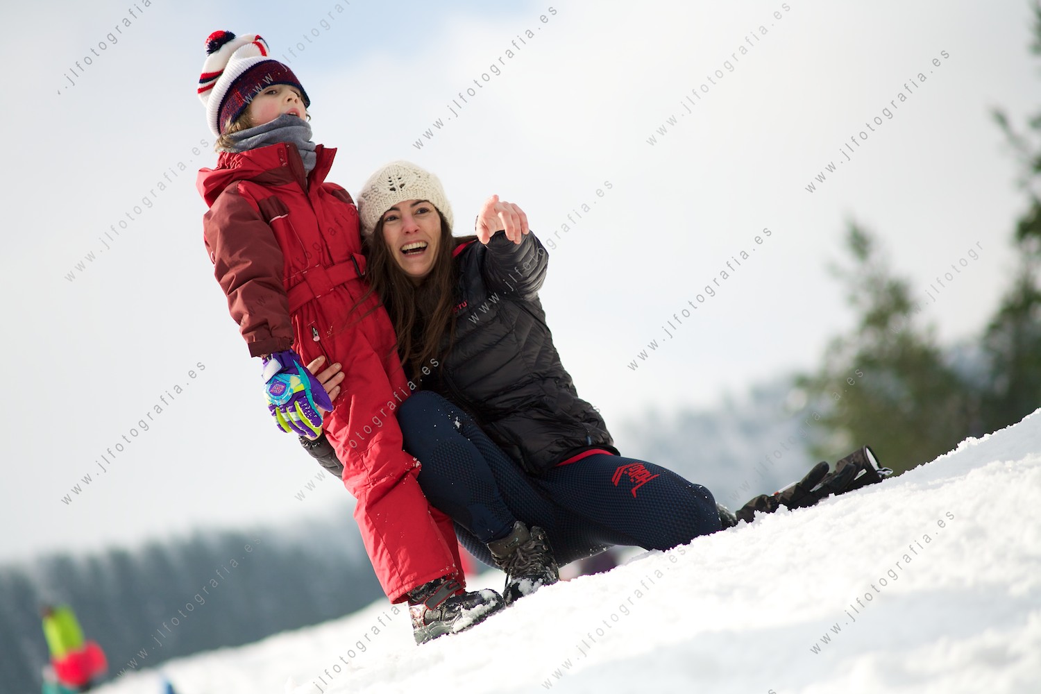 Madre con su hijo disfrutando en la nieve, señalando algo