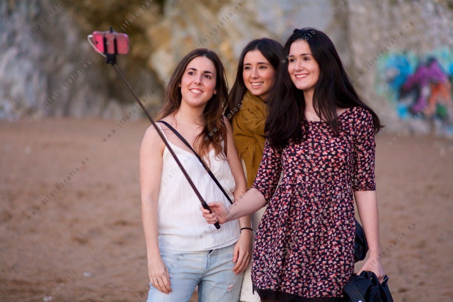 Trío de chicas haciéndose un selfie con el móvil en la playa de Sopelana junto al Peñón