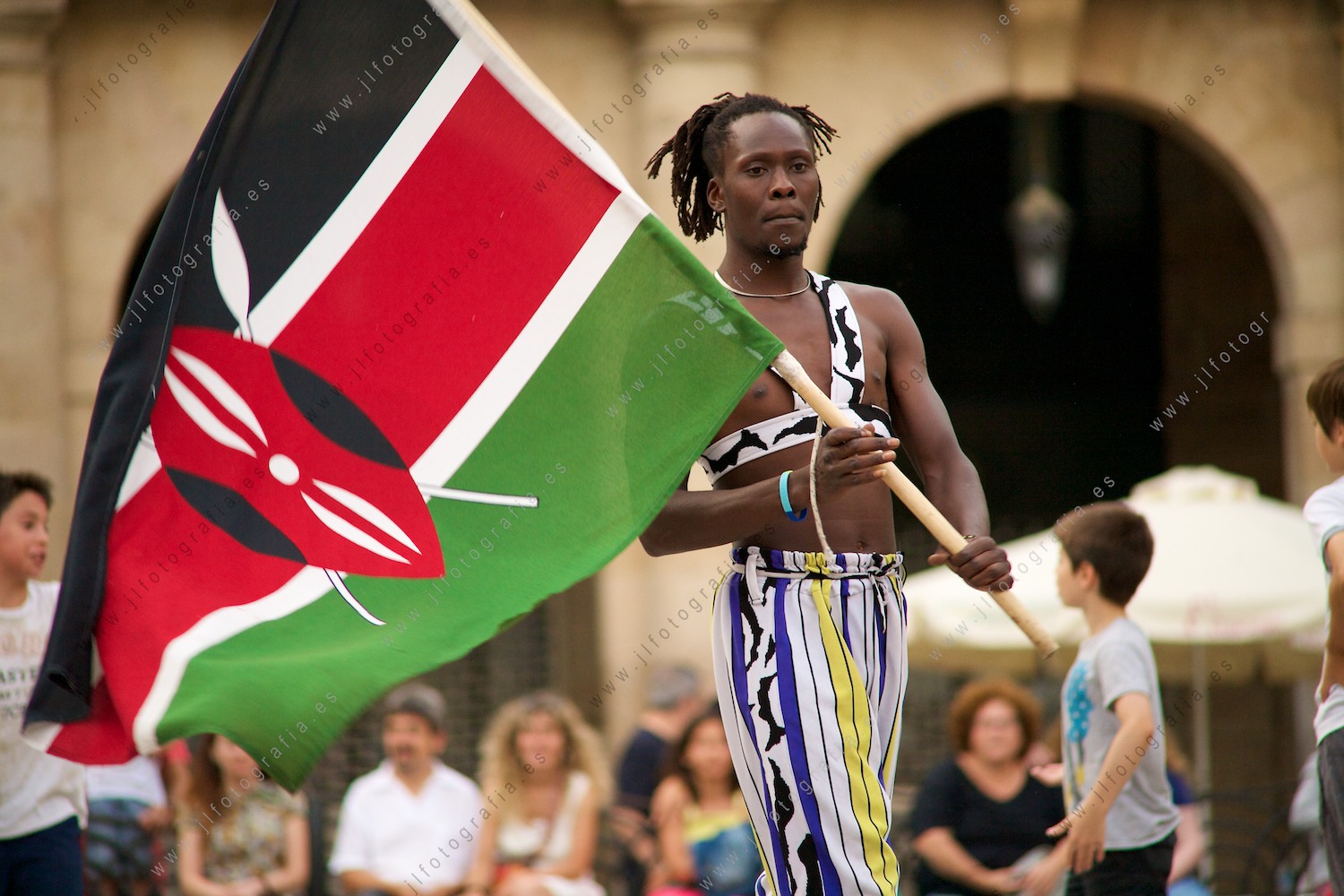 Acróbata keniatra del grupo Afro Jungle Jeegs con la bandera de su país Kenia