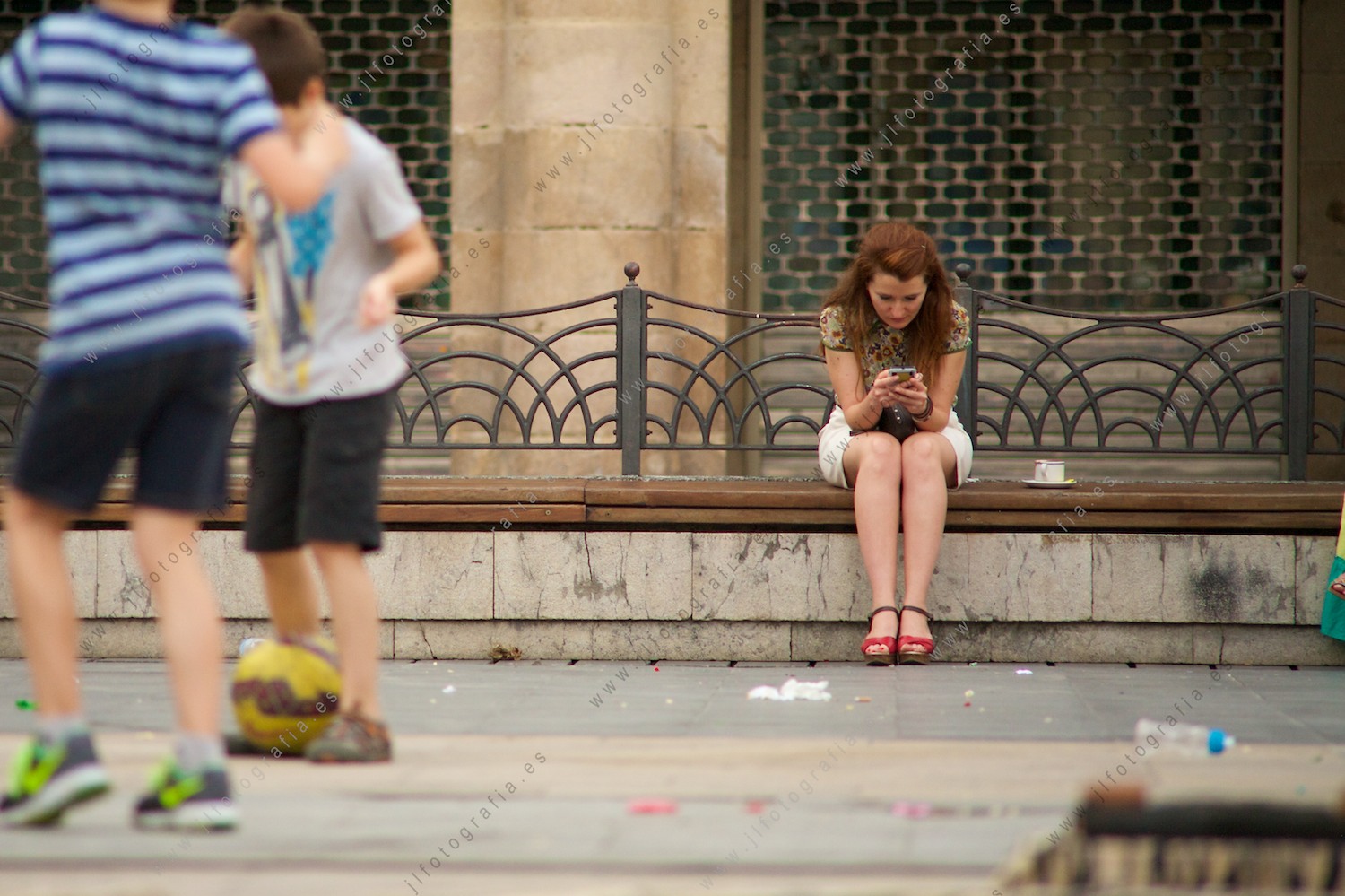 señorita sentada mirando el móvil en la Plaza Nueva de Bilbao