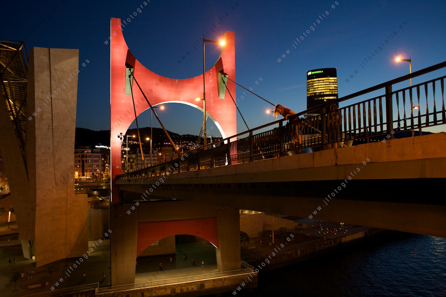 Una chica se asoma peligrosamente en el puente de la Salve, con la torre Iberdrola y el Guggenheim como testigos