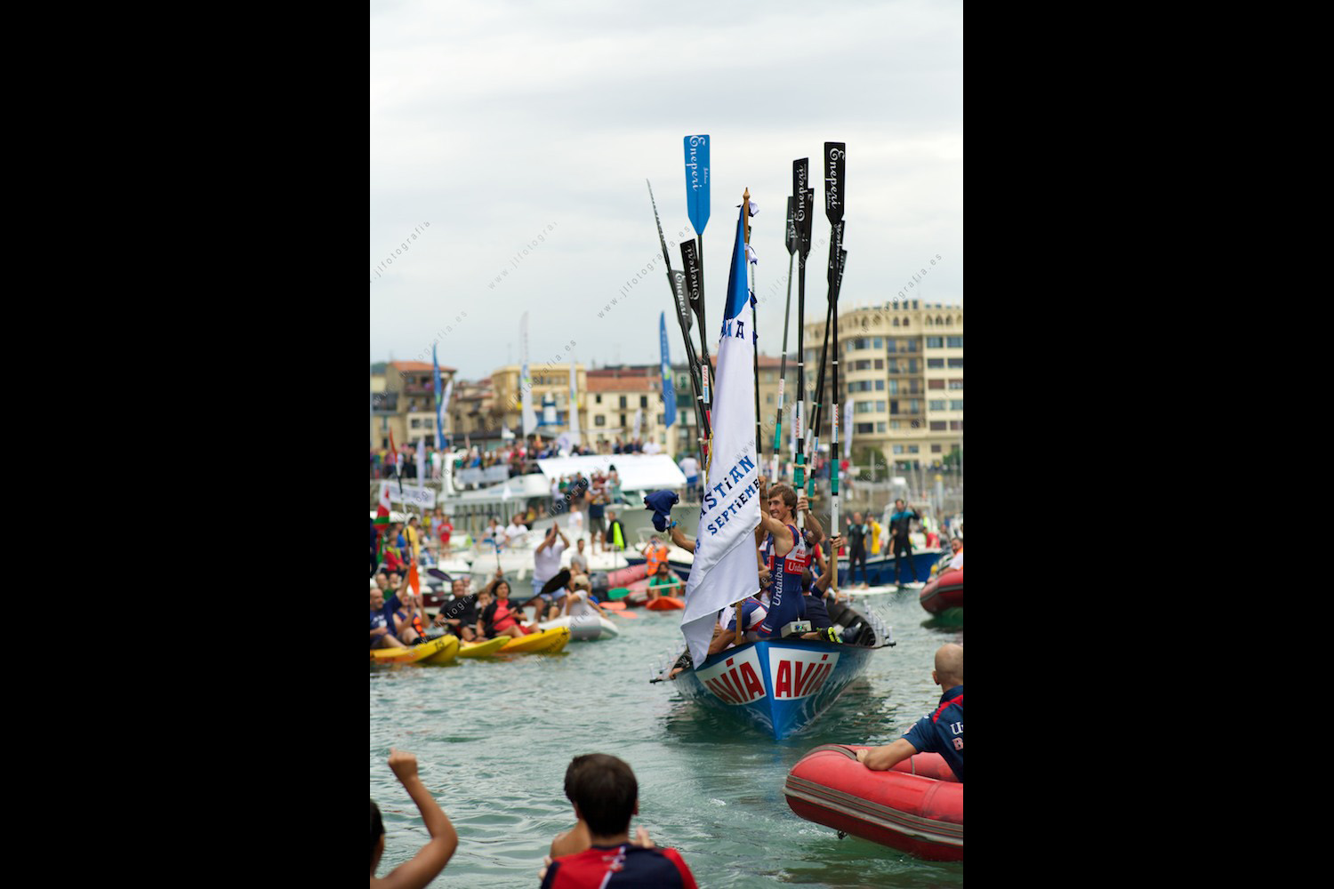 Los vencedores de la edición 2015 de la bandera de la Concha de Donostia llegan a puerto, remos al cielo, jaleados por miles de aficionados