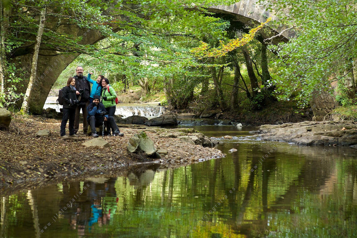 fotógrafos socios de Denbora, posando junto al puente en el río del parque natural del Gorbea en plano general.