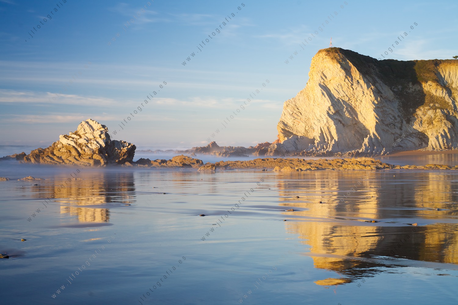 Las rocas del acantilado de la costa vasca, dibujadas en el suelo espejado por el agua del mar