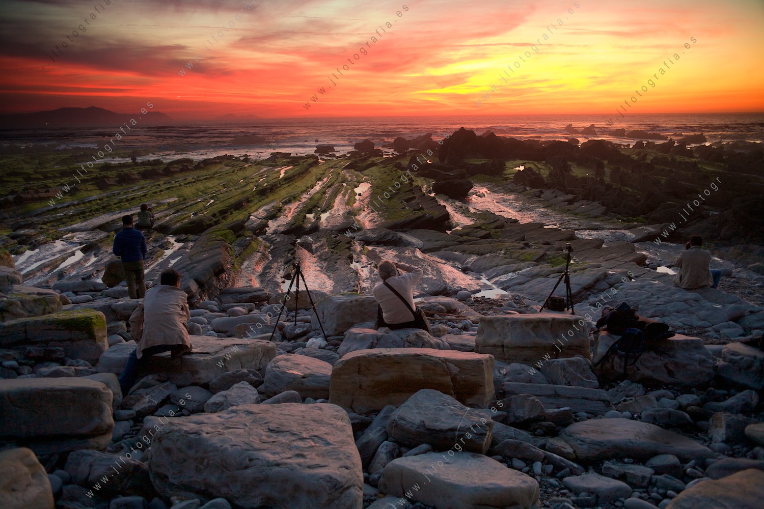 Alumnos de fotografía apostados en la playa de Barrika para retratar el paisaje marino.