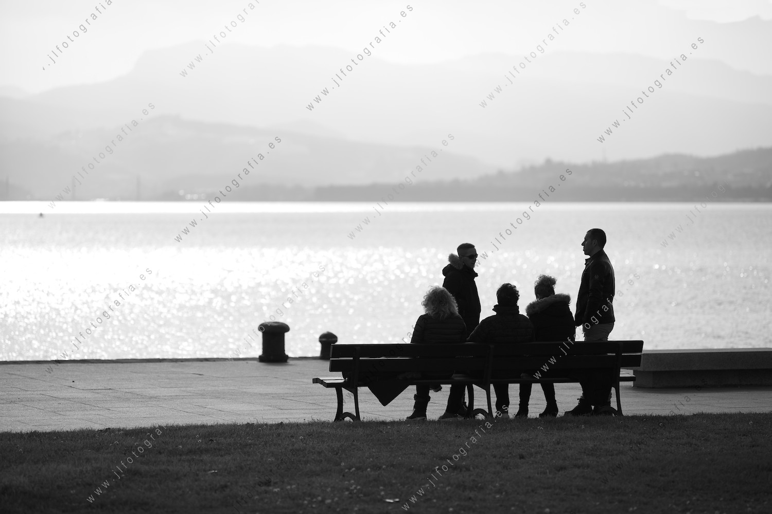 Grupo de personas sentadas en un banco disfrutando el atardecer en Santoña, Cantabria.