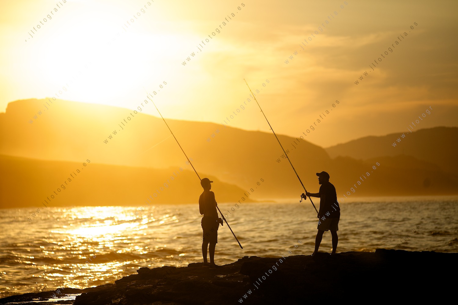 Dos pescadores en las rocas de la playa de El Lastrón, durante la hora dorada.