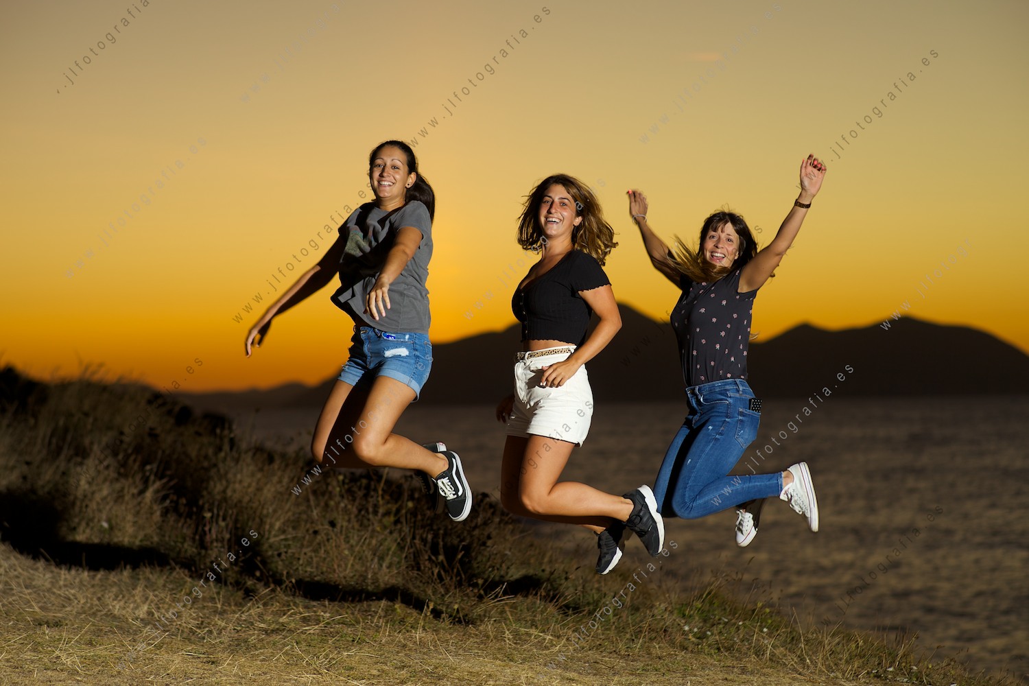Tres jóvenes mujeres saltando al unísono en la costa de Sonabia, Cantabria.