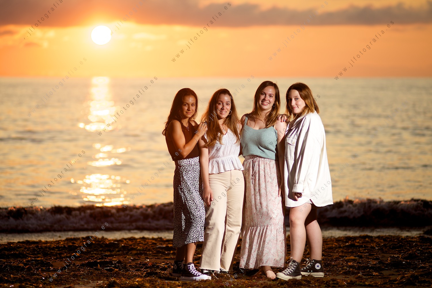 Retrato de un grupo de 4 chicas en el ocaso en la playa.