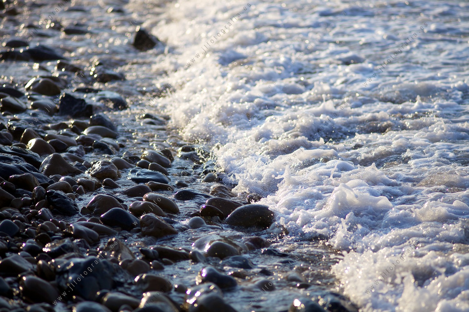 Detalle de las piedras en la orilla de la playa llegando el agua