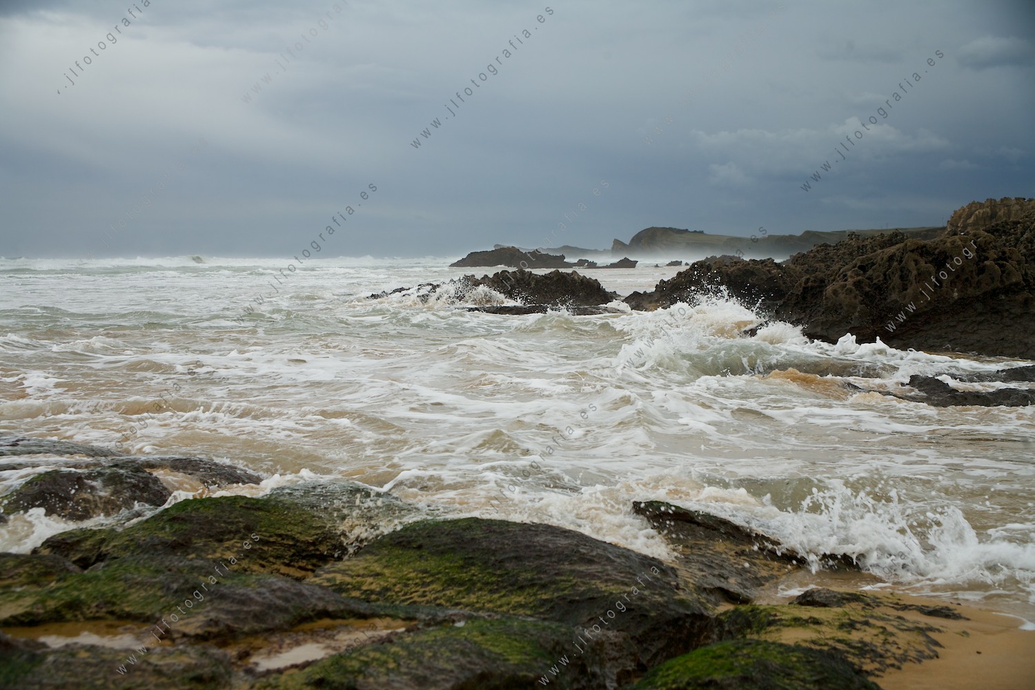 Las olas, bañan las rocas en la costa quebrada de Liencres en Cantabria 