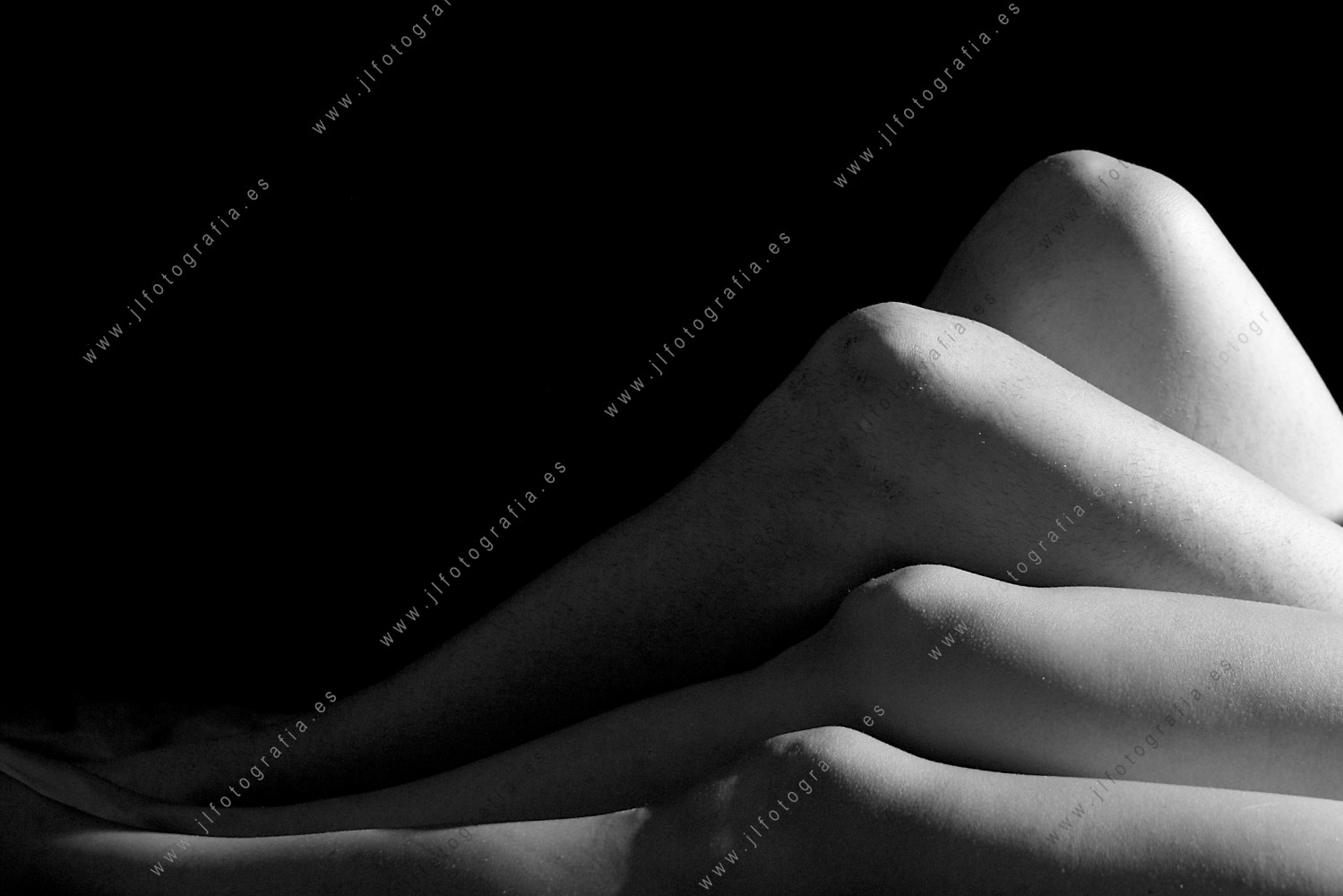 Retrato de estudio de cuerpos desnudos de un hombre y una mujer, detalle de las piernas