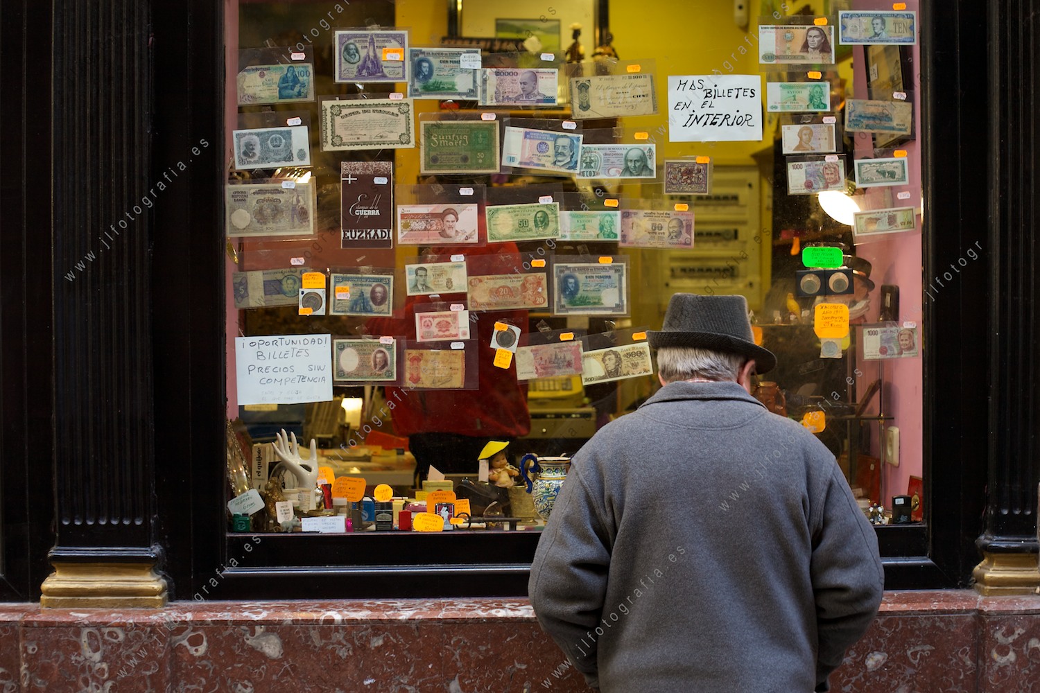 Anciano mirando el escaparate de un comercio de numismática en Bilbao, junto a la plaza Nueva