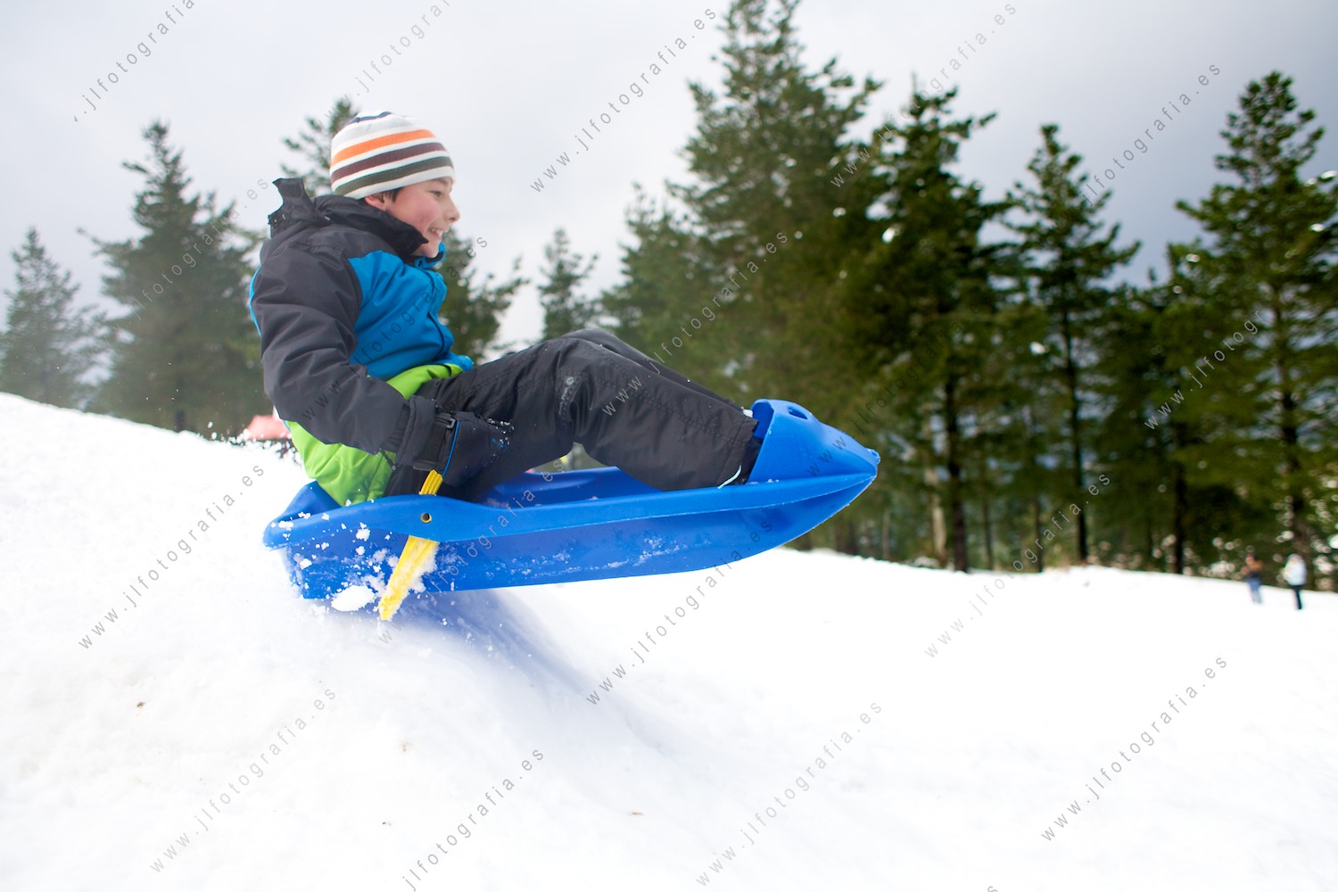 Niño volando de un salto en un trineo de nieve en zalla