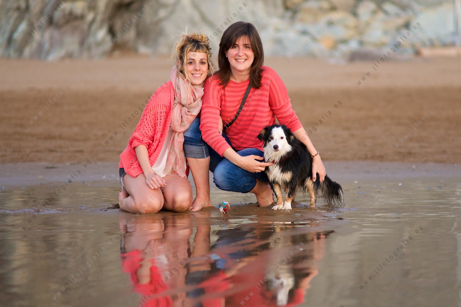 Dos chicas posando en plano completo con su perro en la playa 