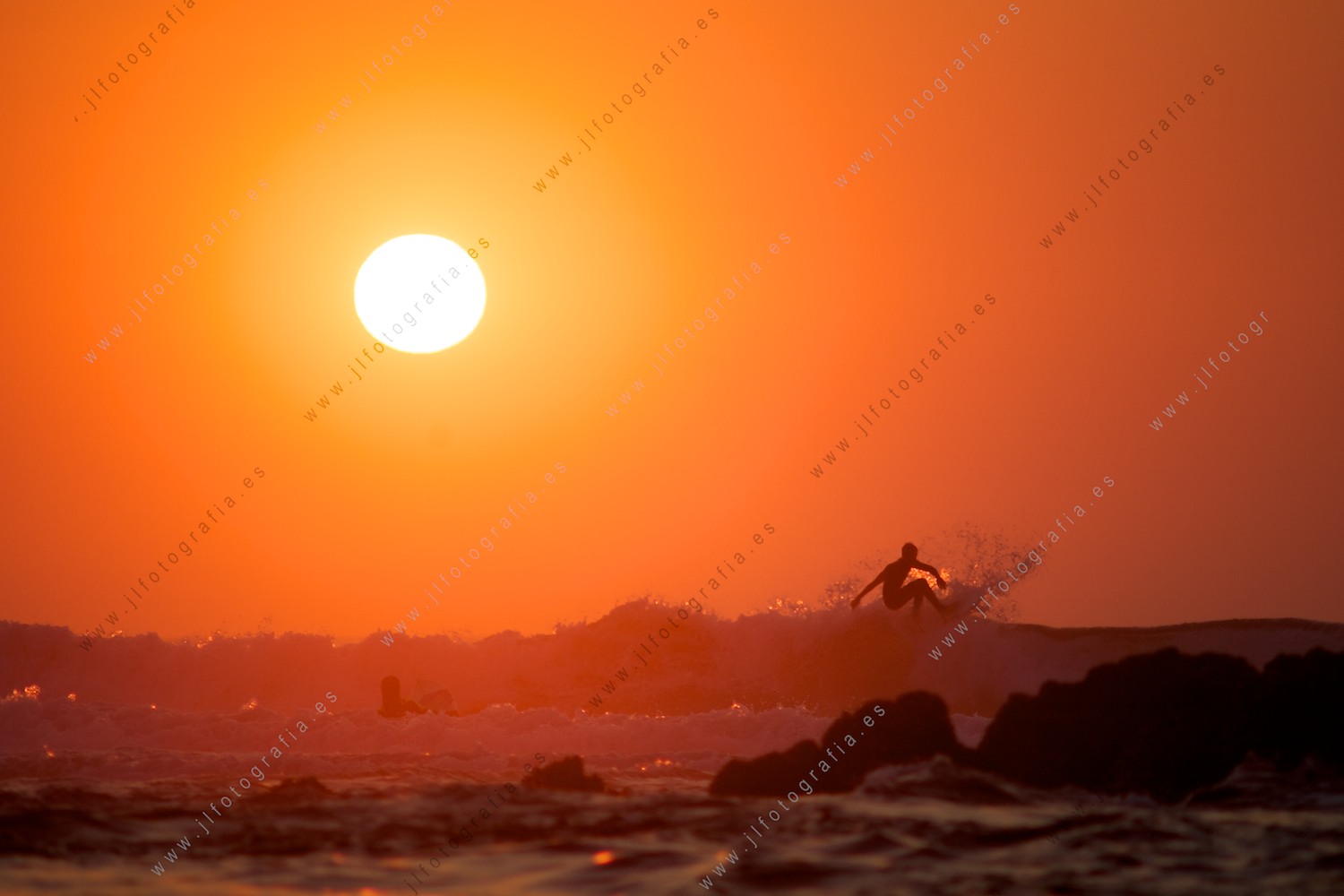 Surfista haciendo un aereo sobre la cresta de la ola bajo el sol