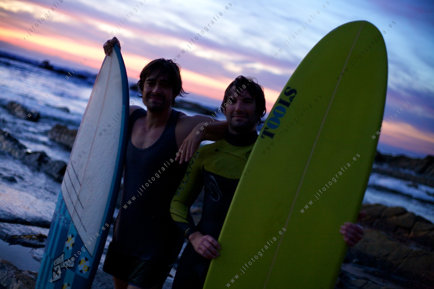 Posado, retrato de dos surfistas al final de la jornada, casi sin luz en el cielo