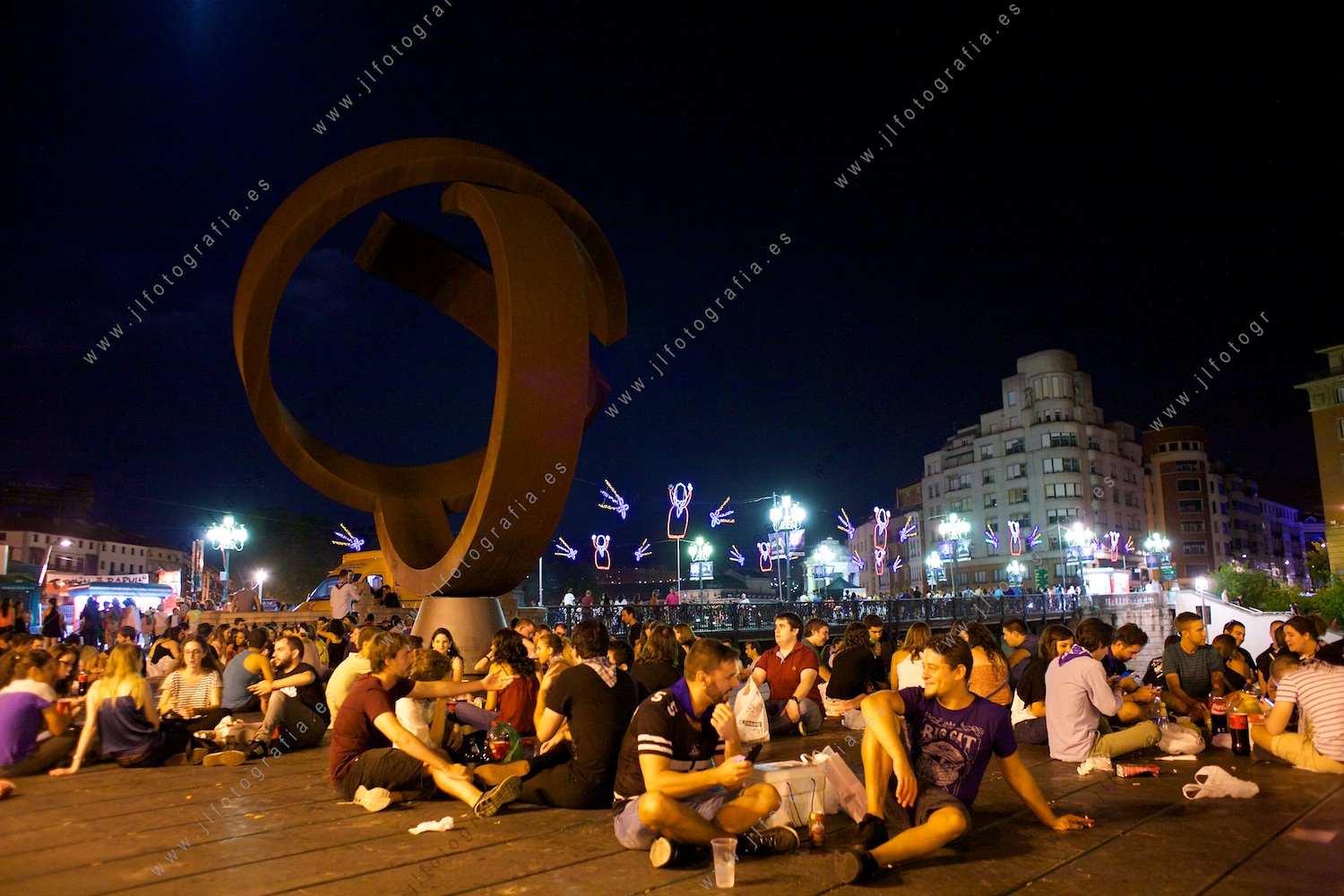 la gente se sienta junto a la variante ovoide esperando para ver los fuegos artificiales de la aste nagusia de Bilbao