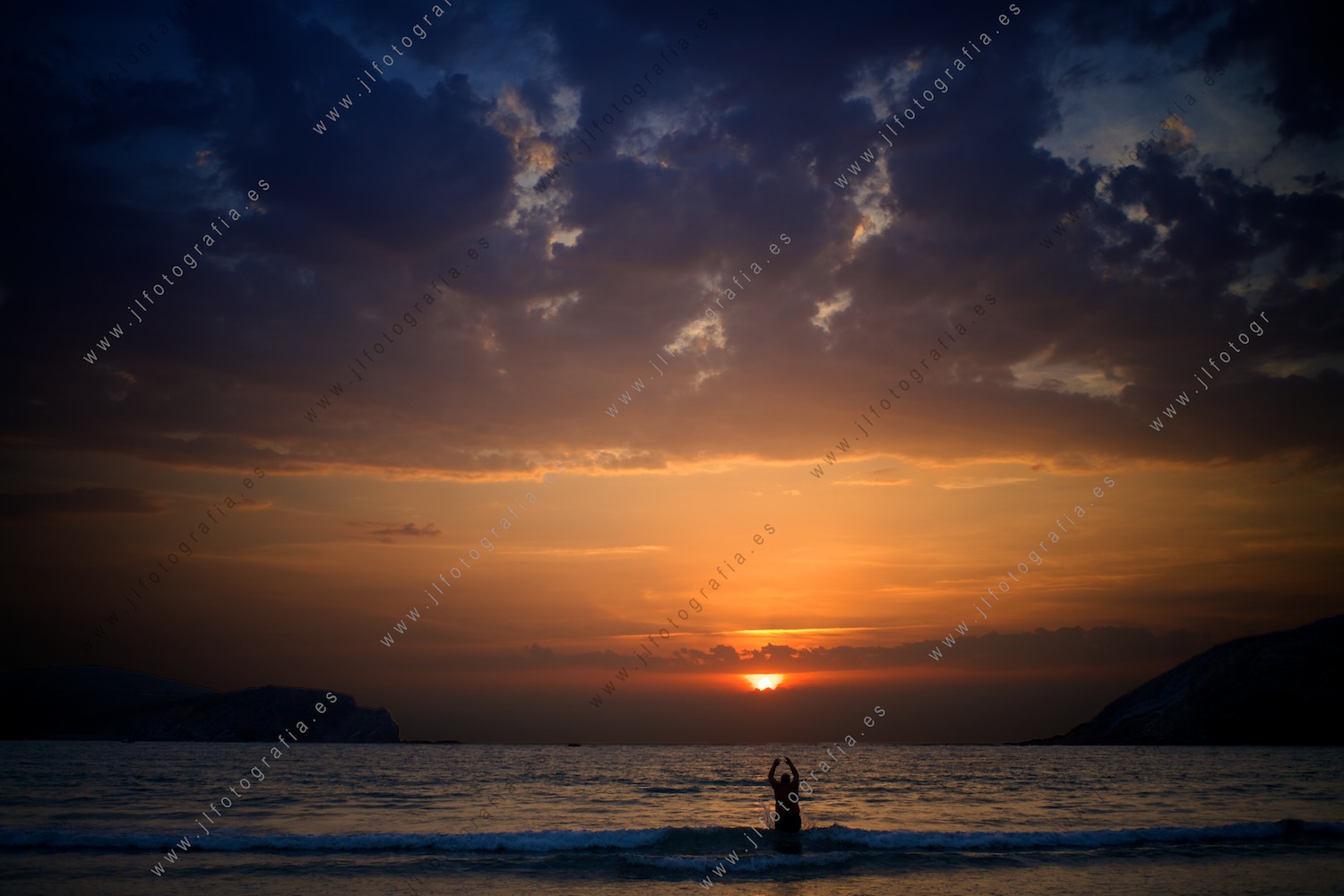 Un anciano que aprovecha la hermosa puesta de sol para darse el último baño del día en la playa de Plentzia