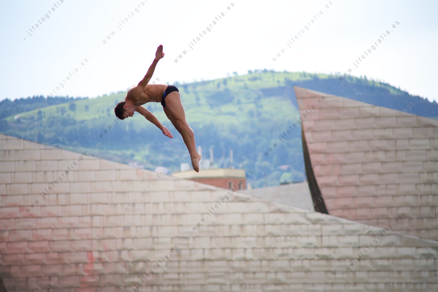 un saltador clavadista, realizando sus mortales con el museo Guggenheim de testigo