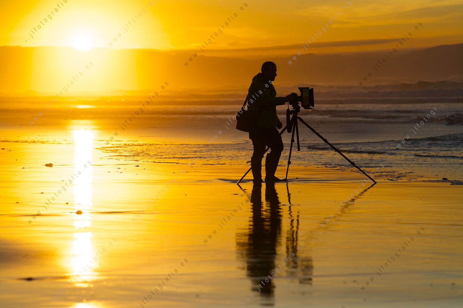 Fotógrafo de Denbora en la orilla de la playa de Sopelana con un trípode en el ocaso.