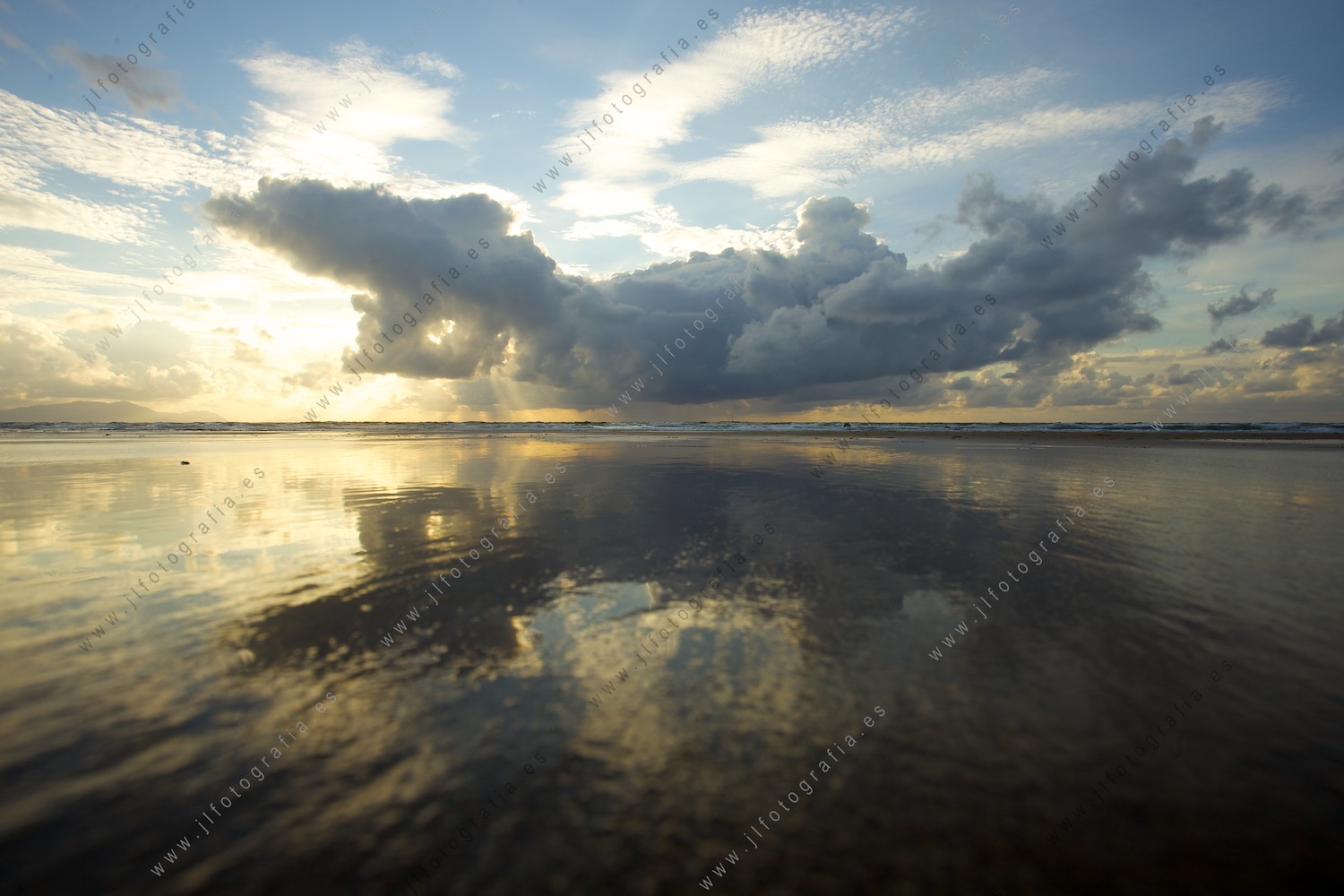 Reflejo del cielo en la oriya de la playa en marea baja.